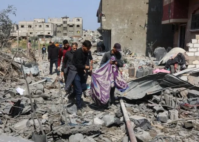 Palestinos carregam corpo retirado dos escombros de uma casa destruída pelos ataques israelense - Omar Al-Qattaa / AFP